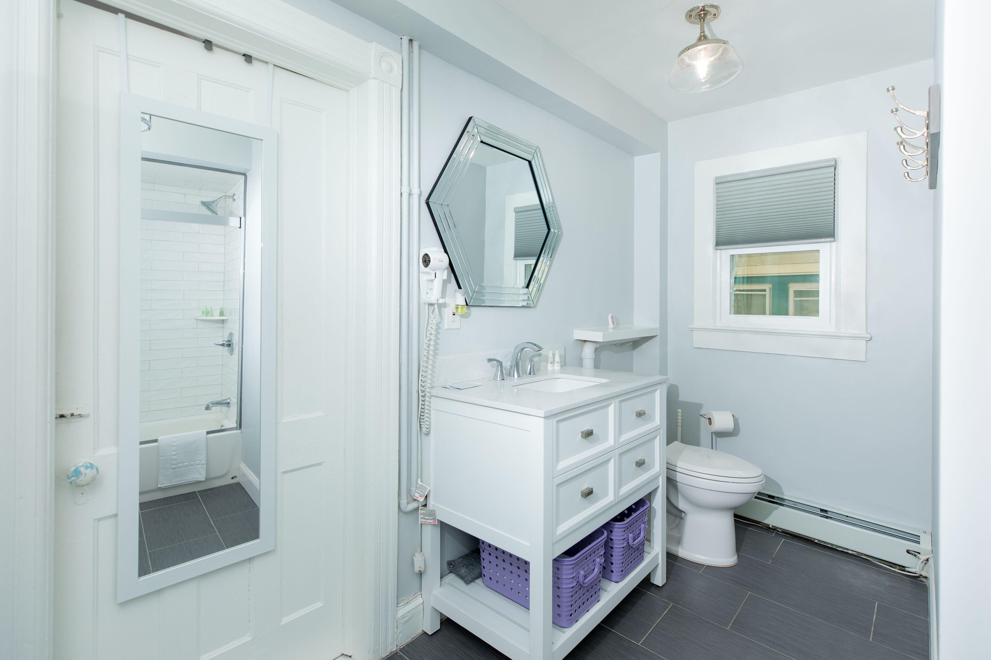 A bathroom with a white vanity, a mirror, a toilet, and a shower.