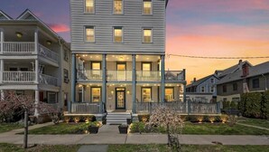 A two-story building with a balcony on the second floor, a porch with string lights, and a front door. - The Inn at Ocean Grove (Ocean Grove)