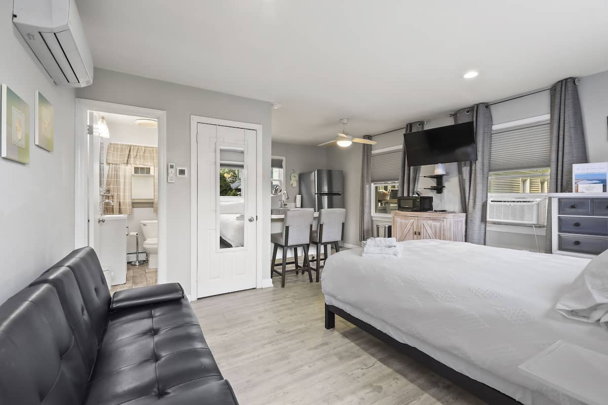 A modern hotel room with a large bed, a sofa, a desk, and a TV.