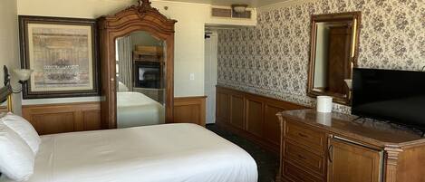 A hotel room with two beds, a wooden dresser, a television, and a framed picture on the wall.