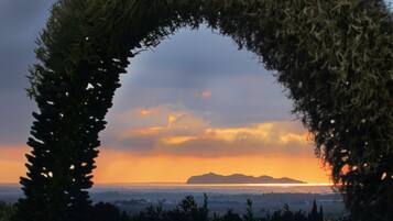 Une arche naturelle qui s’élève et encadre la vue sur un coucher de soleil au-dessus d’un paysage côtier.