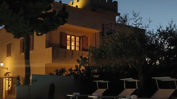 Un edificio con piscina y sillones de descanso.