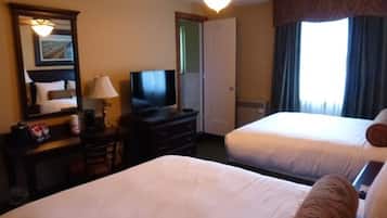 Habitación de hotel con dos camas, un televisor, ventilador de techo y ventana con cortinas.