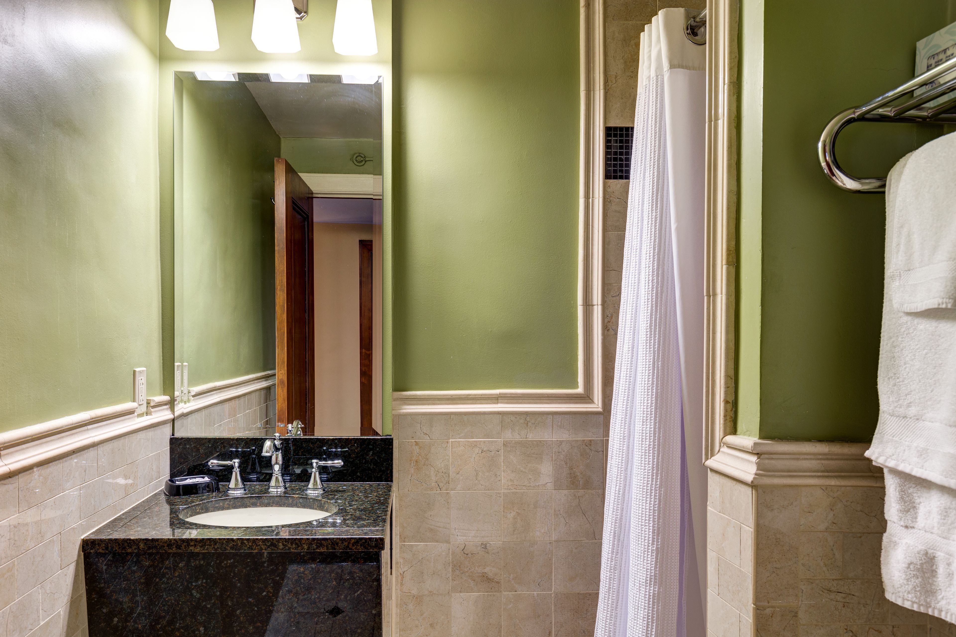 A bathroom with a sink, mirror, and shower curtain.
