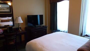 Une chambre d’hôtel avec un grand lit, un bureau équipé d’une télévision, d’une lampe et d’une chaise.