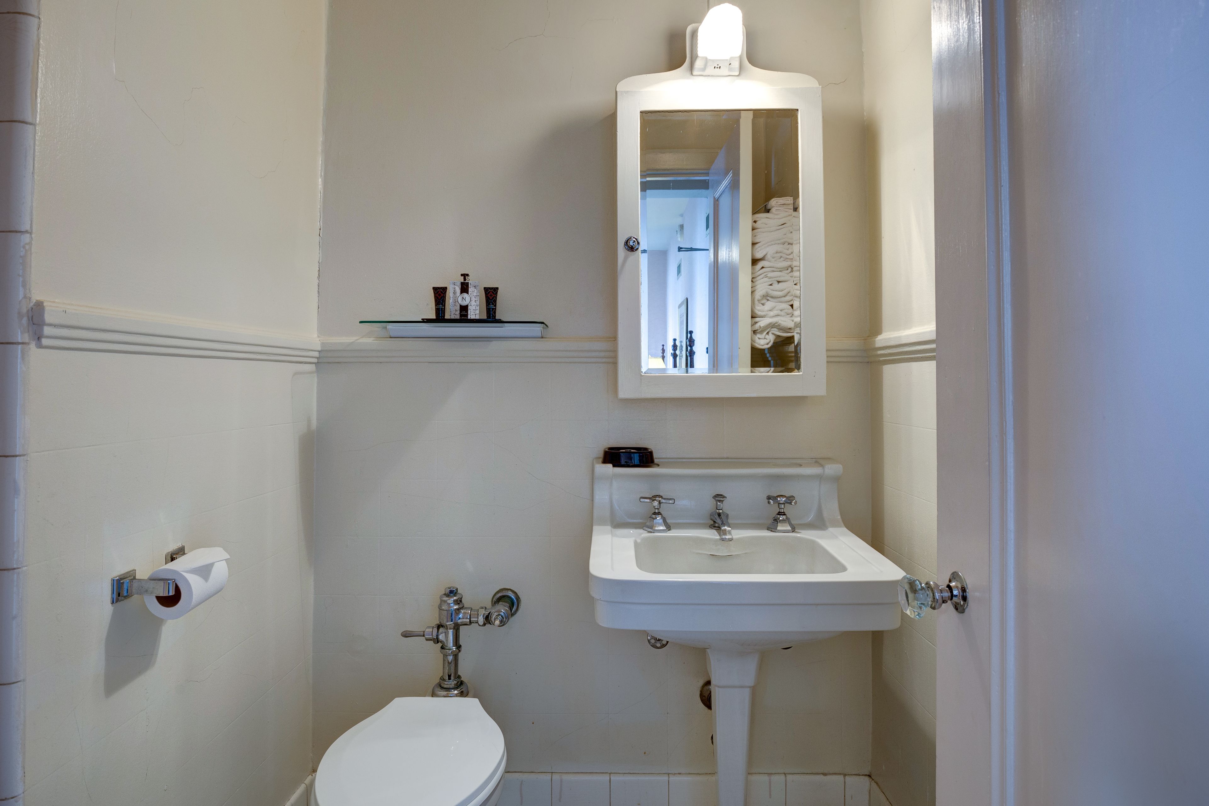 A bathroom with a toilet, sink, and mirror.