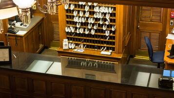 A reception desk with a glass top, wooden paneling, a chandelier, and a wall-mounted display of folded towels.