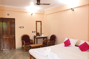 Une chambre d’hôtel avec un lit, deux chaises, une petite table, un miroir et une porte.
