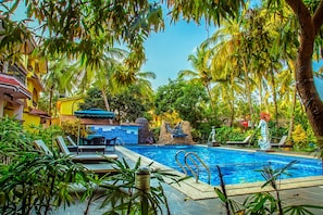 Une piscine avec des chaises longues et un mur en pierre.