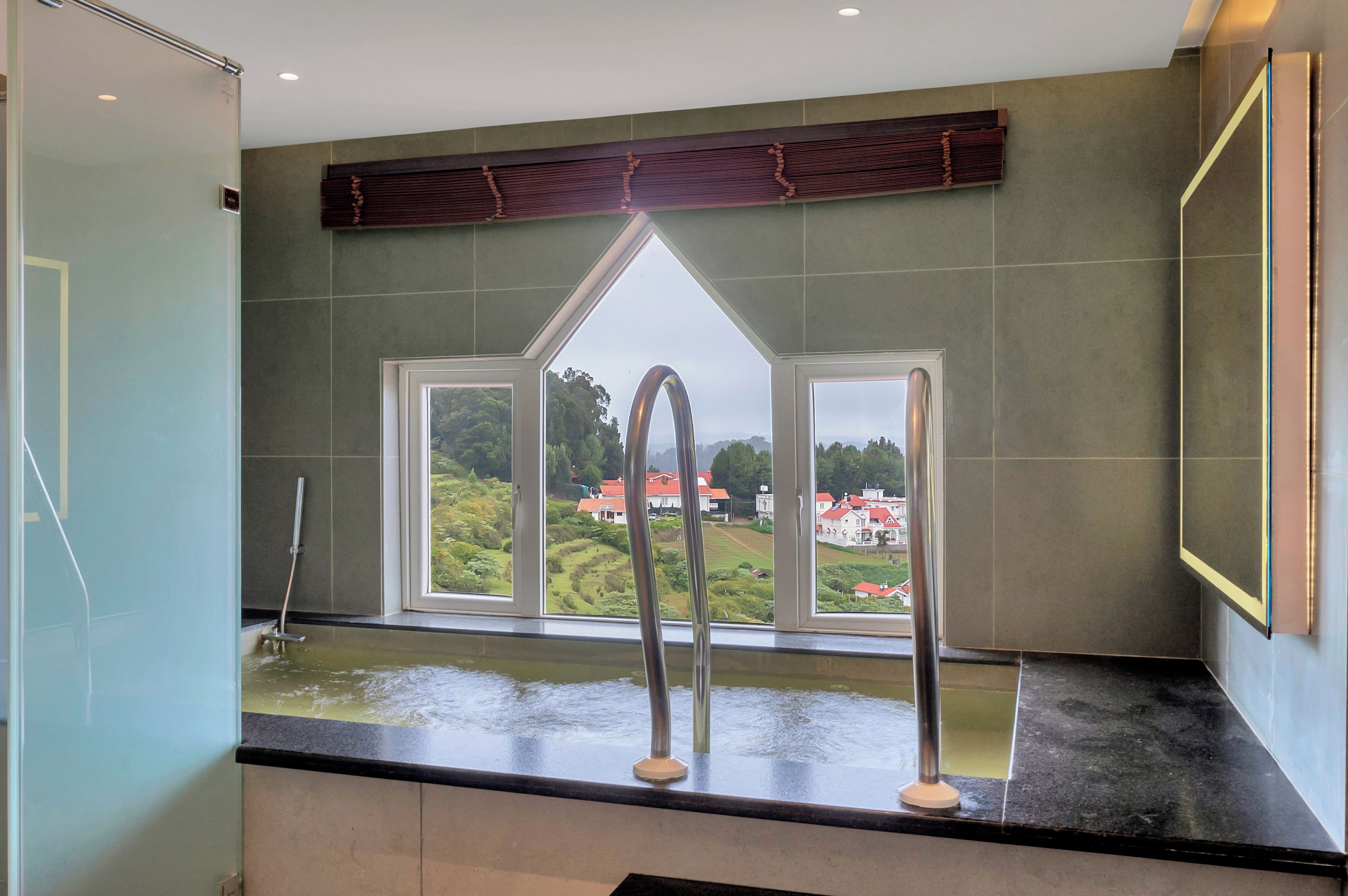 A bathroom with a bathtub, a window with a view of a landscape, and a towel rack.