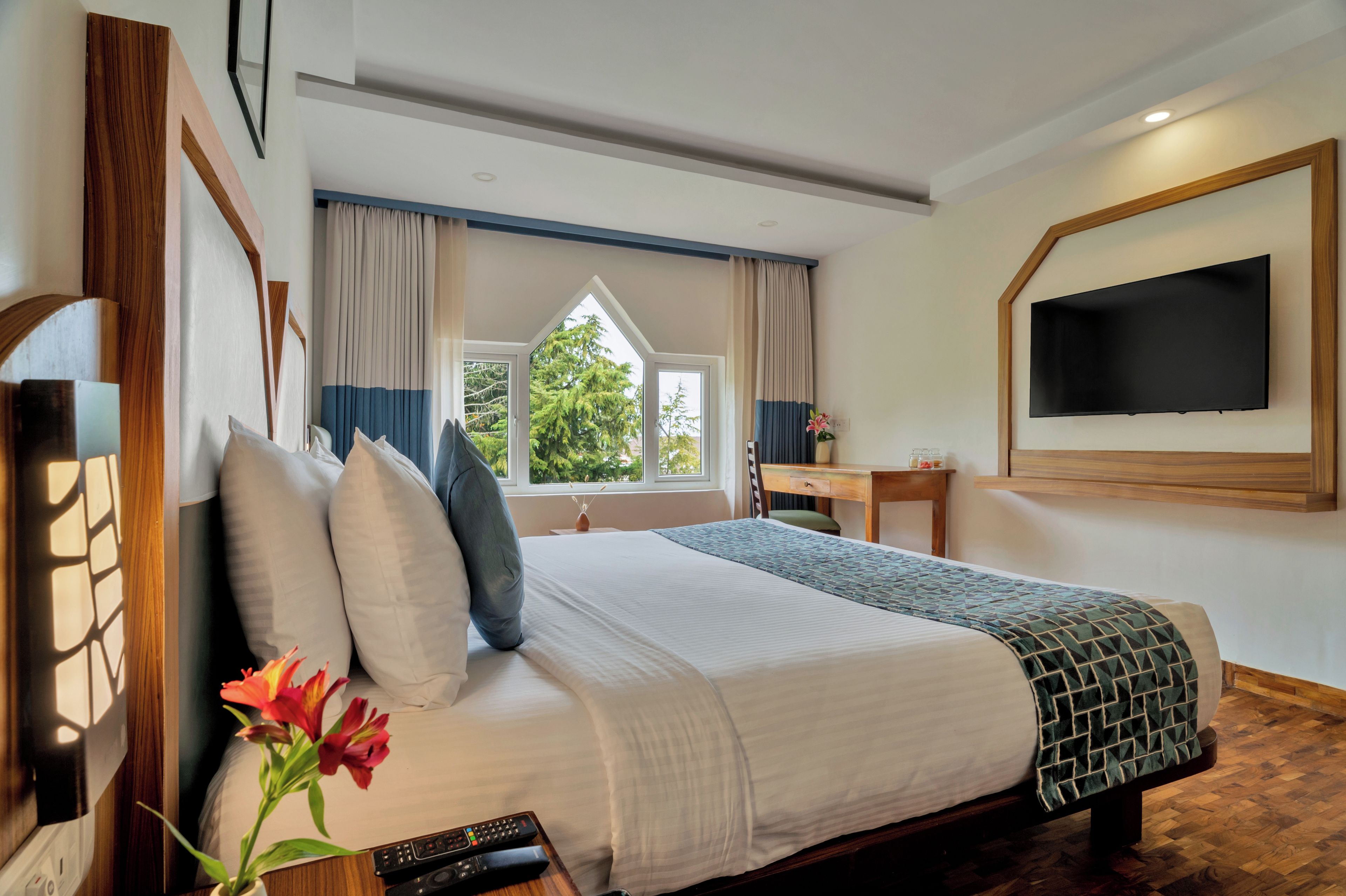 Ein Hotelzimmer mit Bett, Schreibtisch, Fernseher und einem Fenster mit Vorhängen.
