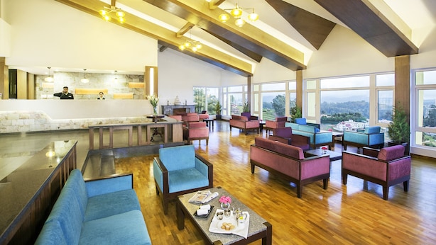 A spacious lobby with a bar area, seating arrangements, and large windows offering a view of the landscape.