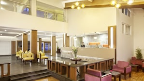 A spacious lobby with a reception desk, multiple seating areas, and a staircase leading to an upper level.
