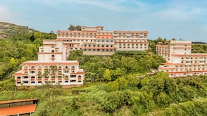 A large, multi-story hotel with a consistent architectural style, located on a hillside surrounded by lush greenery.