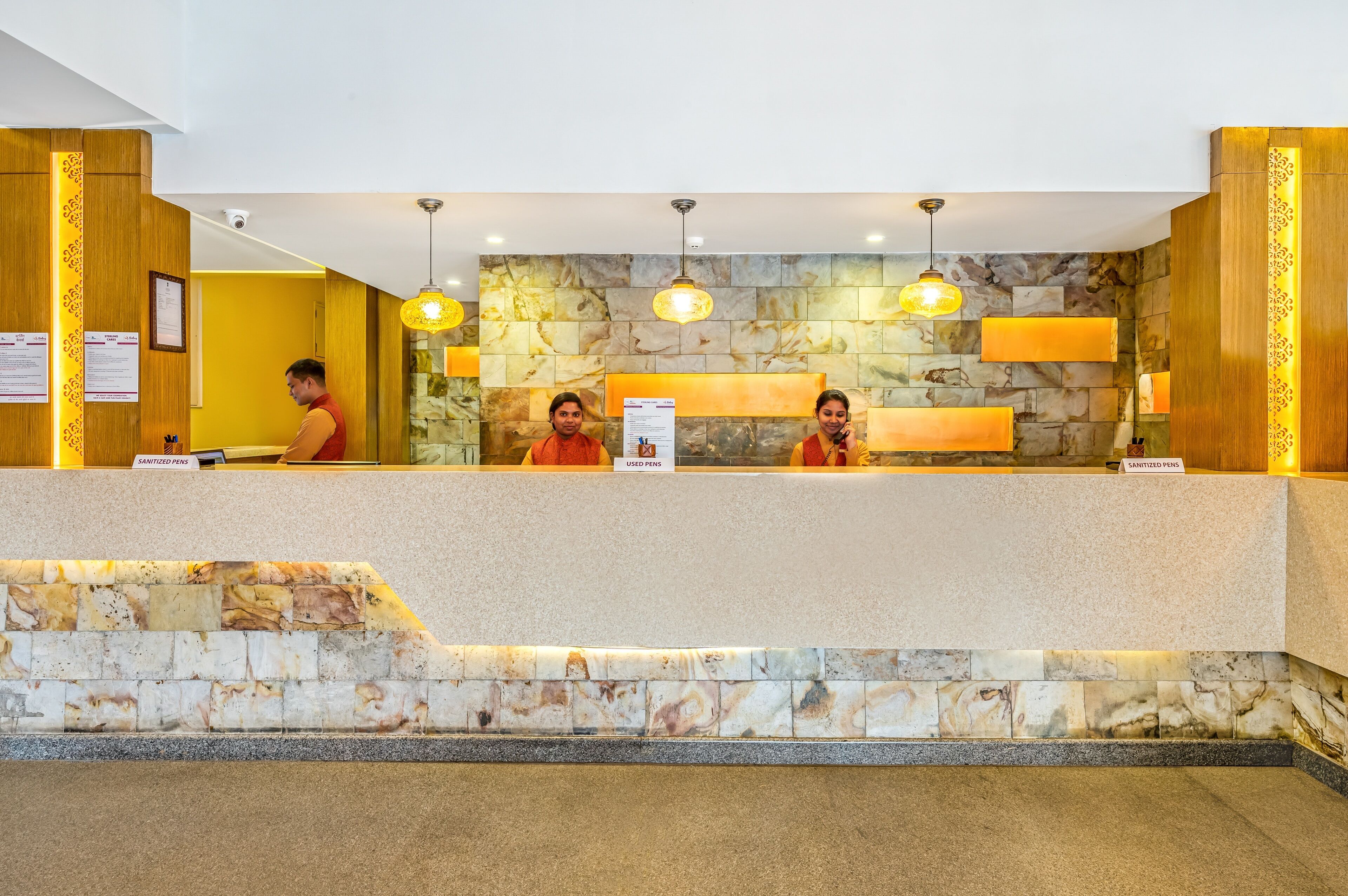 A reception desk with a stone wall backdrop, a wooden panel design, and a sign indicating a sanitized pen area.