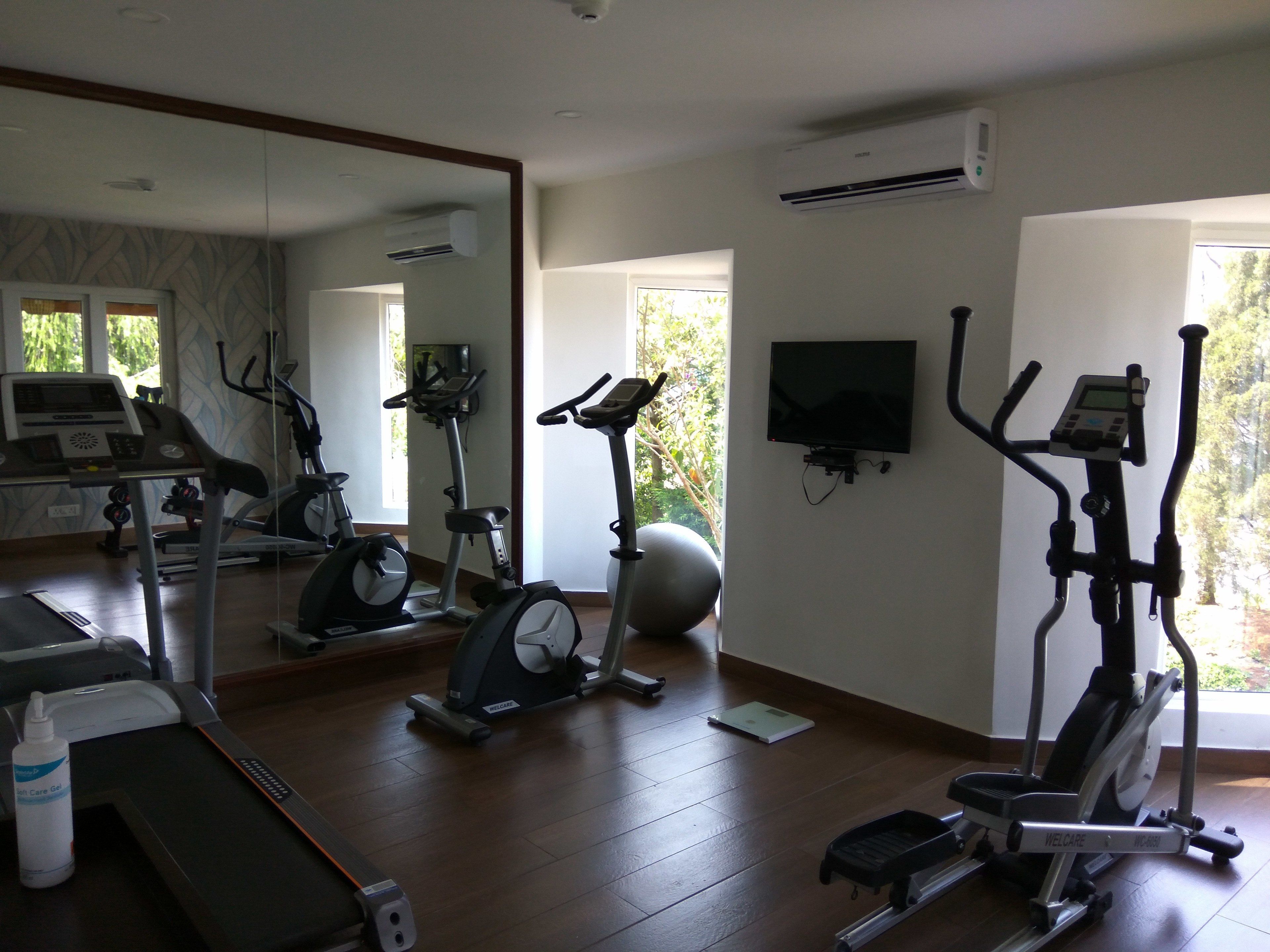Une salle de sport équipée de matériel d’exercice, dotée d’un grand miroir et d’un téléviseur fixé au mur.