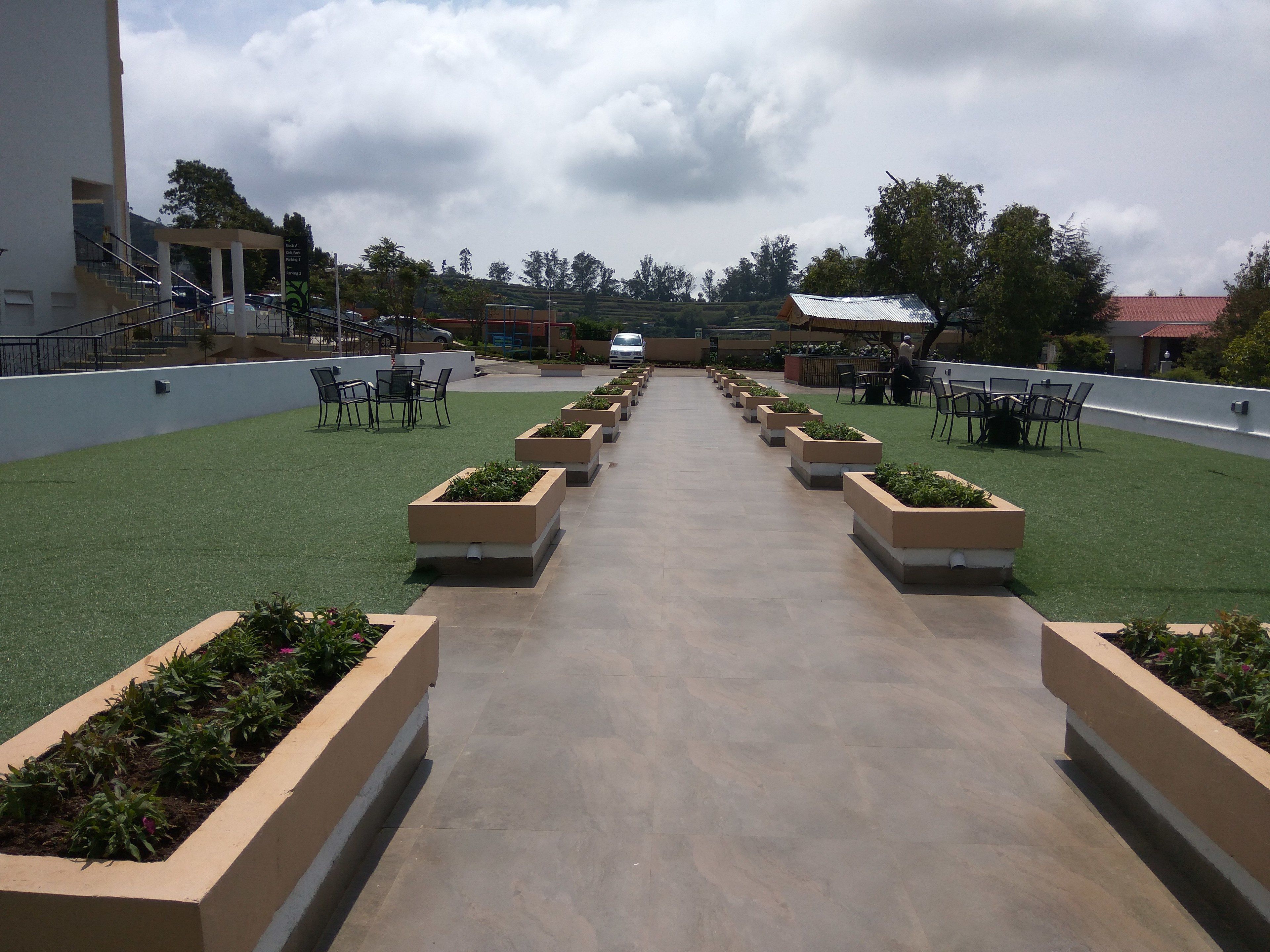 A rooftop terrace with a central pathway flanked by planters and outdoor seating.