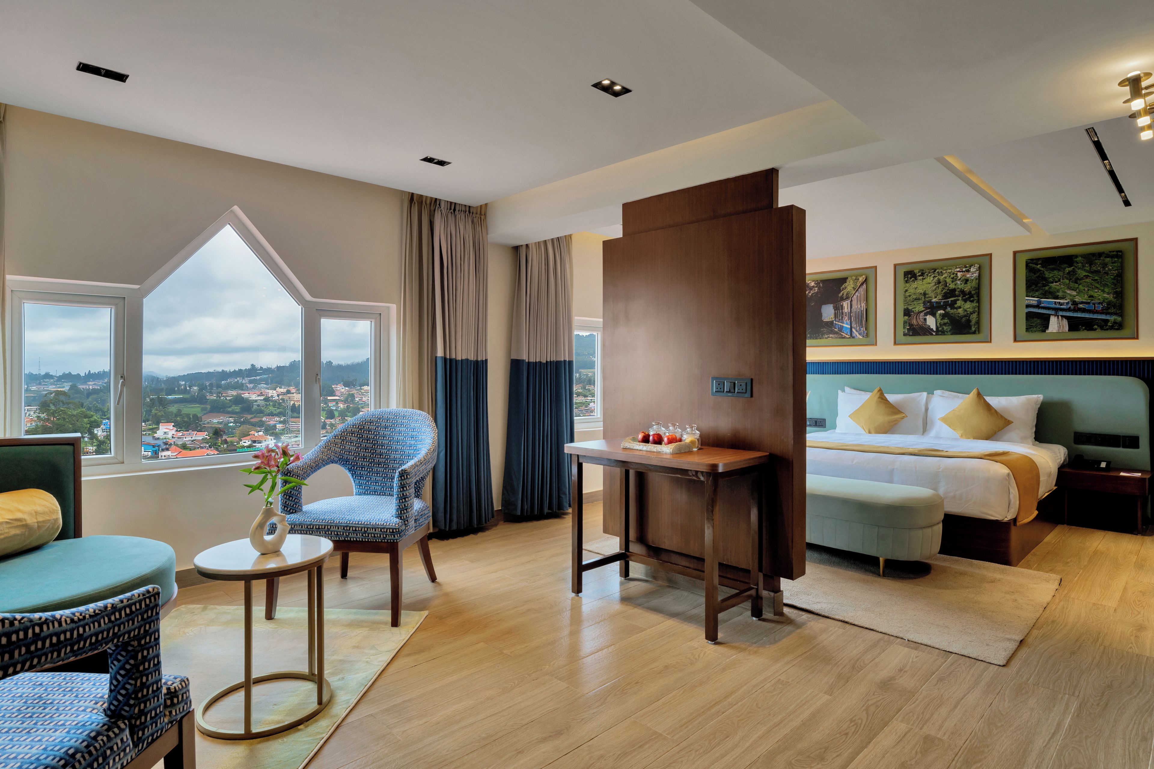 A hotel room with a large window, a bed, a desk, and a chair.