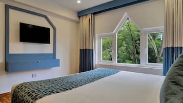 A bedroom with a bed, a television mounted on the wall, and a window with curtains.