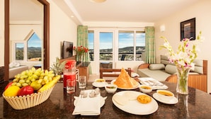 A dining area with a table set for breakfast, including fruits, bread, and bowls of soup.
