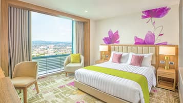 Habitación de hotel con una cama grande, dos mesitas de noche, una silla y vistas a la ciudad a través de amplios ventanales.