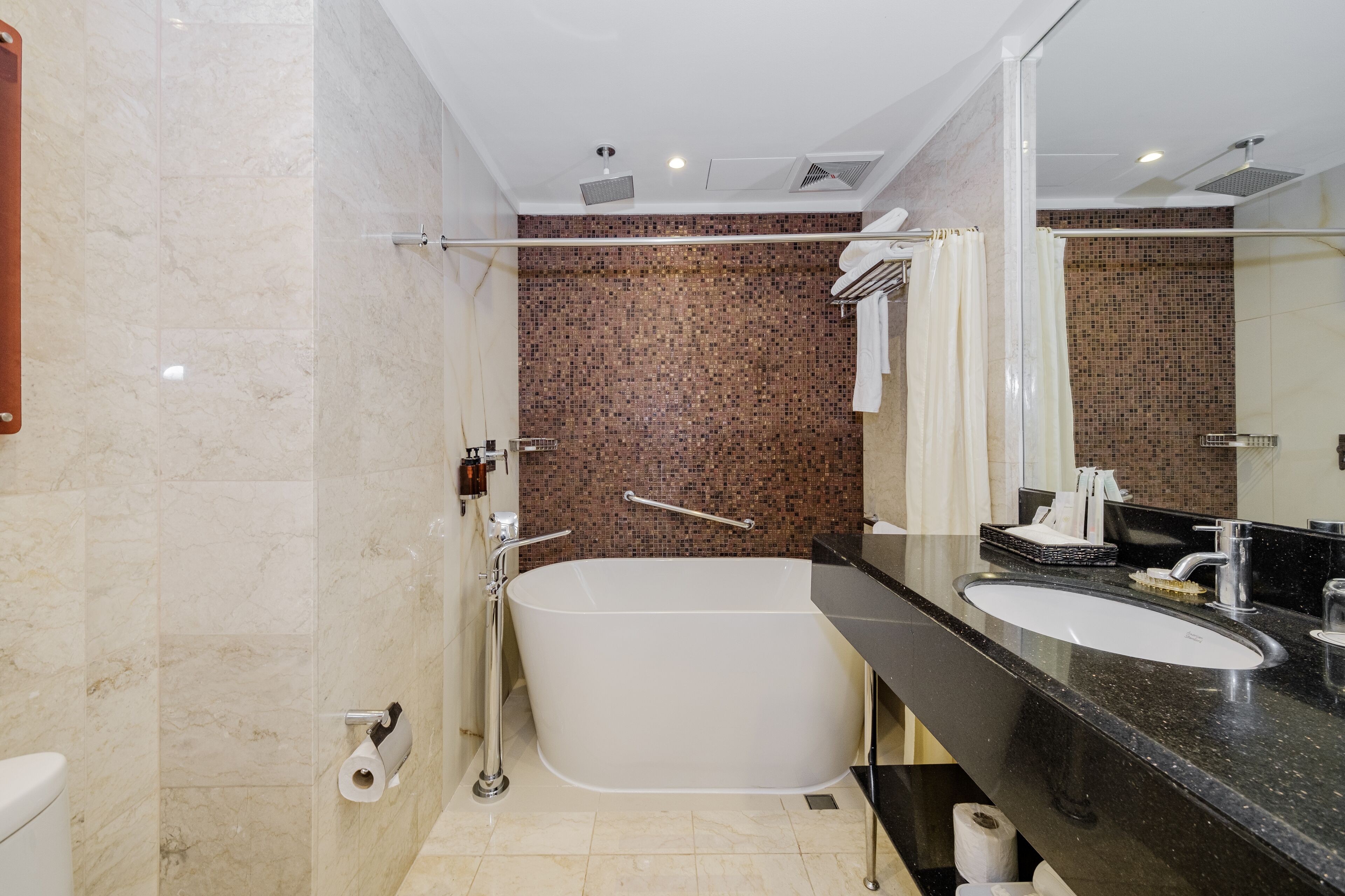 A modern bathroom with a freestanding bathtub, a large mirror, and a black countertop sink.