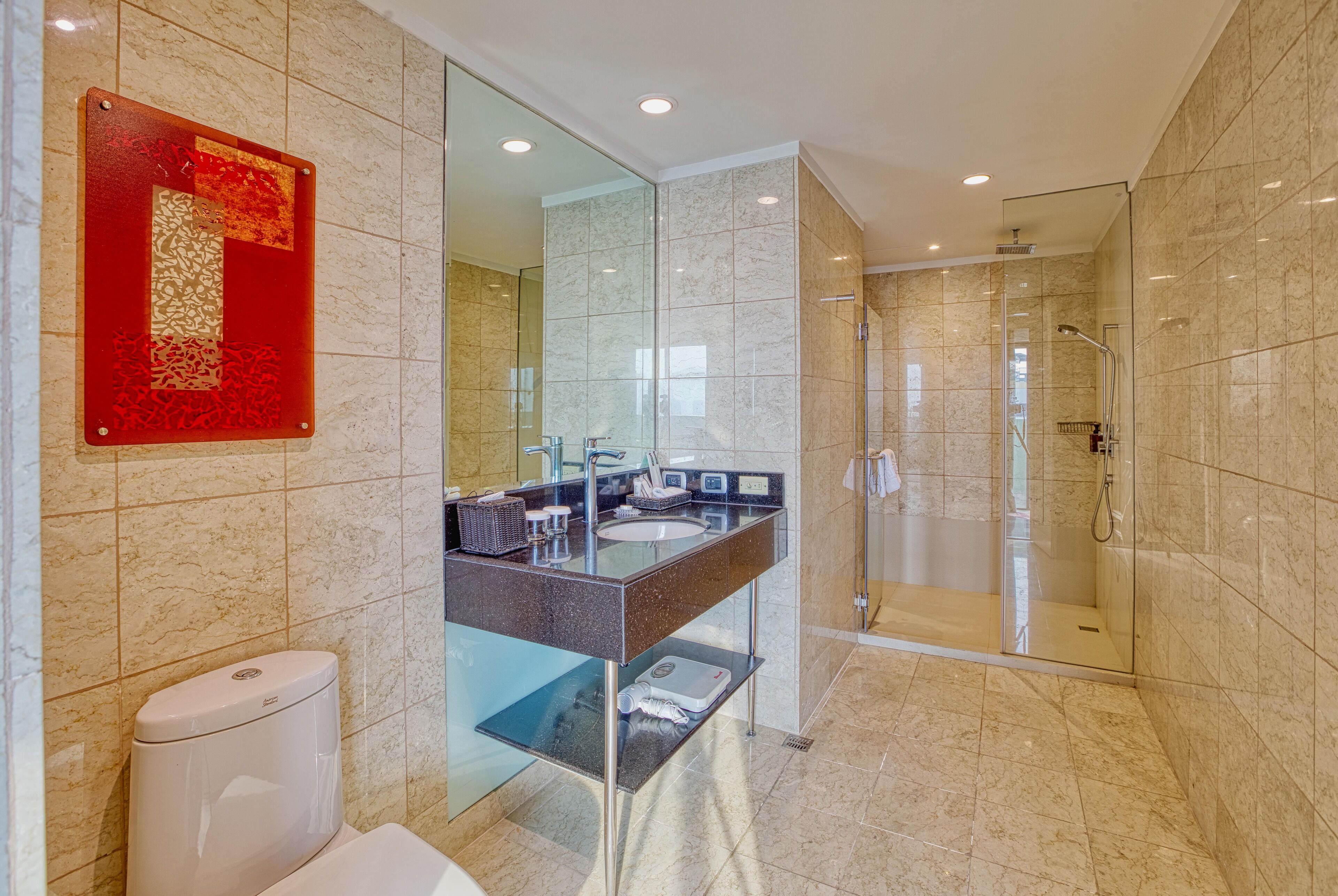 A modern bathroom with a glass shower enclosure, a glass sink, and a toilet.