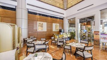 Un hall d’hôtel moderne avec un sol en marbre, de nombreuses tables et des chaises.