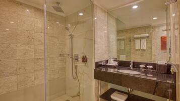 A modern bathroom with a glass-enclosed shower, a black marble sink, and a large mirror.