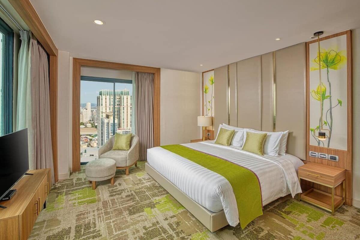 Een hotelkamer met een bed, een televisie, een stoel, een nachtkastje en een schilderij.
