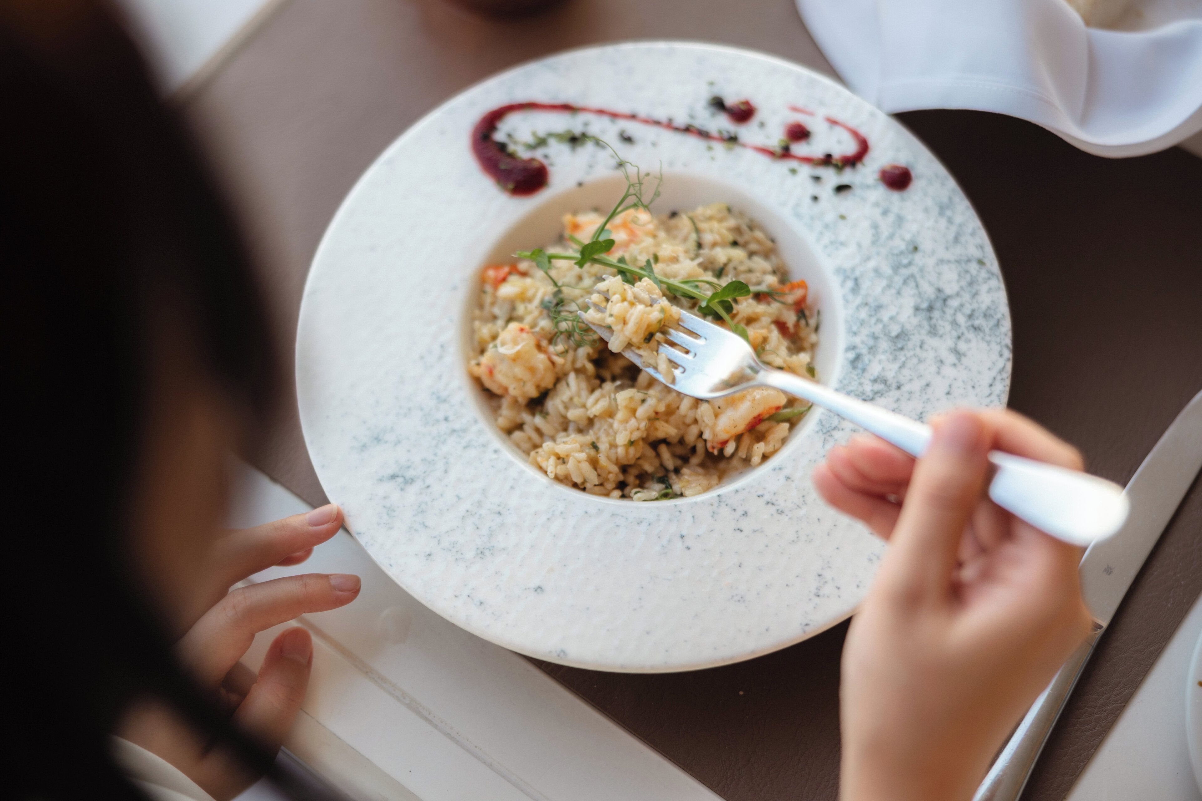A person dining with a plate of food and a fork.