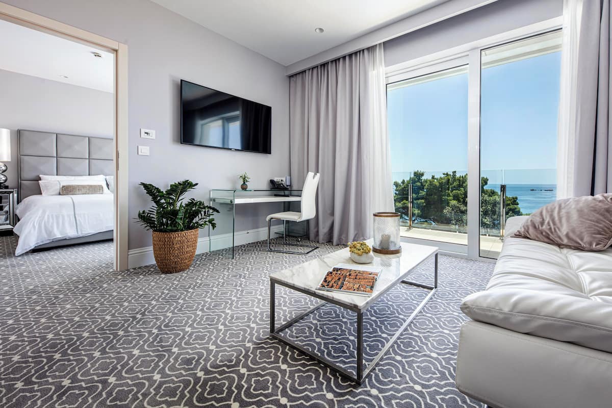 Quarto de hotel moderno com uma cama grande, um sofá, uma escrivaninha e uma televisão.