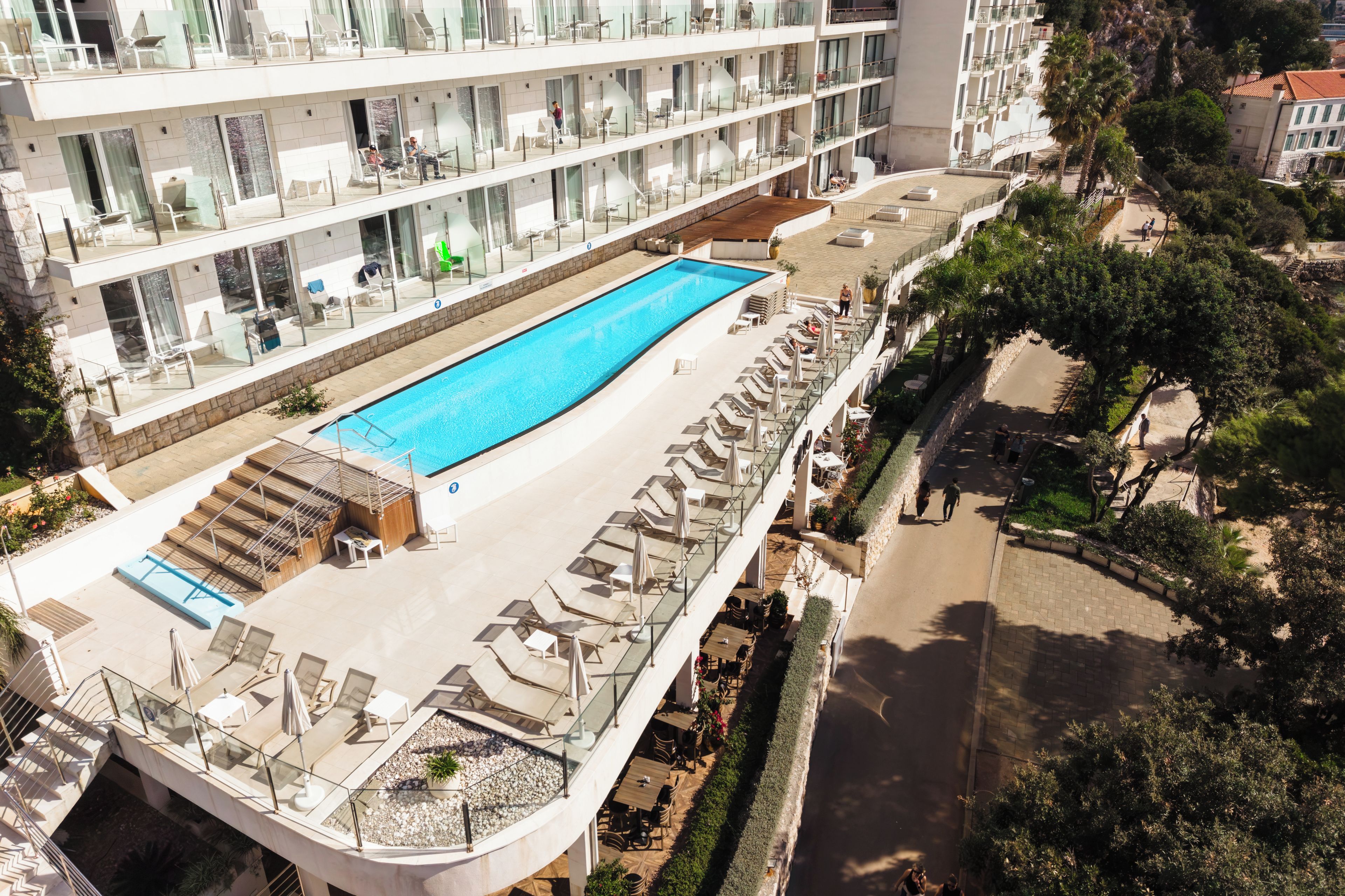 A rooftop pool with sun loungers and a glass balustrade.