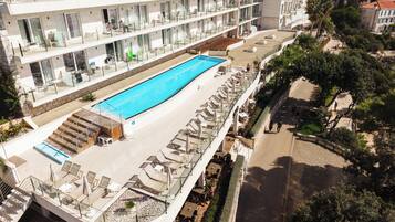 A rooftop pool with sun loungers and a glass balustrade.