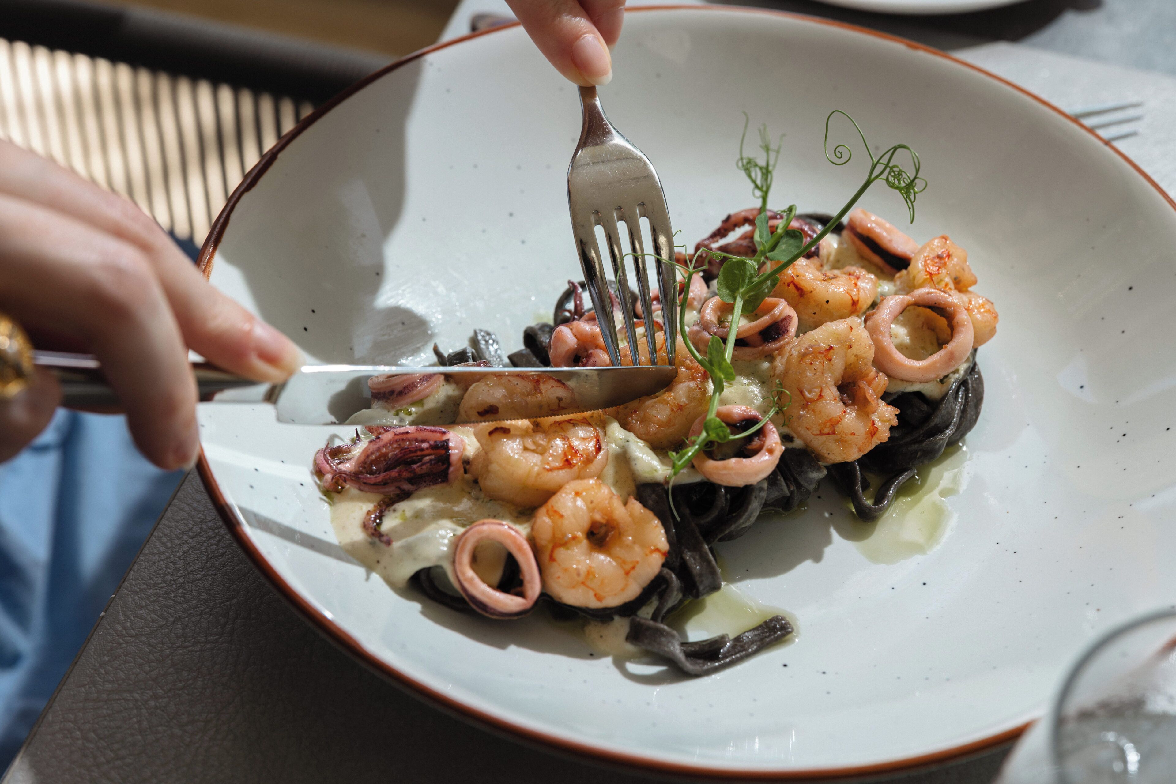A plate of seafood pasta with a fork and knife.