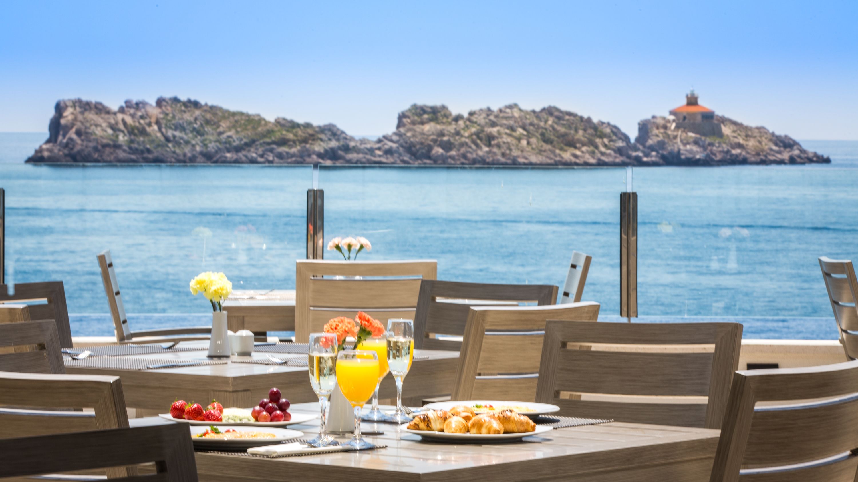 A table set for breakfast with a view of the sea and rocky islands.