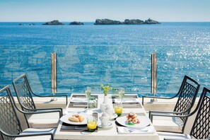 Mesa posta para dois, vista para o mar e ilhas ao fundo.