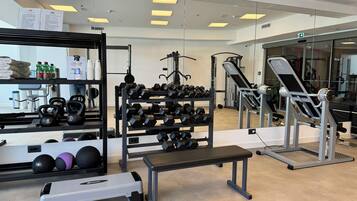 A gym with exercise equipment, a step platform, and a bench.