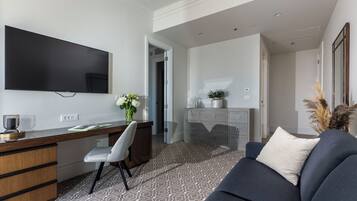 Una sala de estar moderna con un televisor de pantalla plana, un escritorio con una silla, un sofá y un jarrón decorativo.