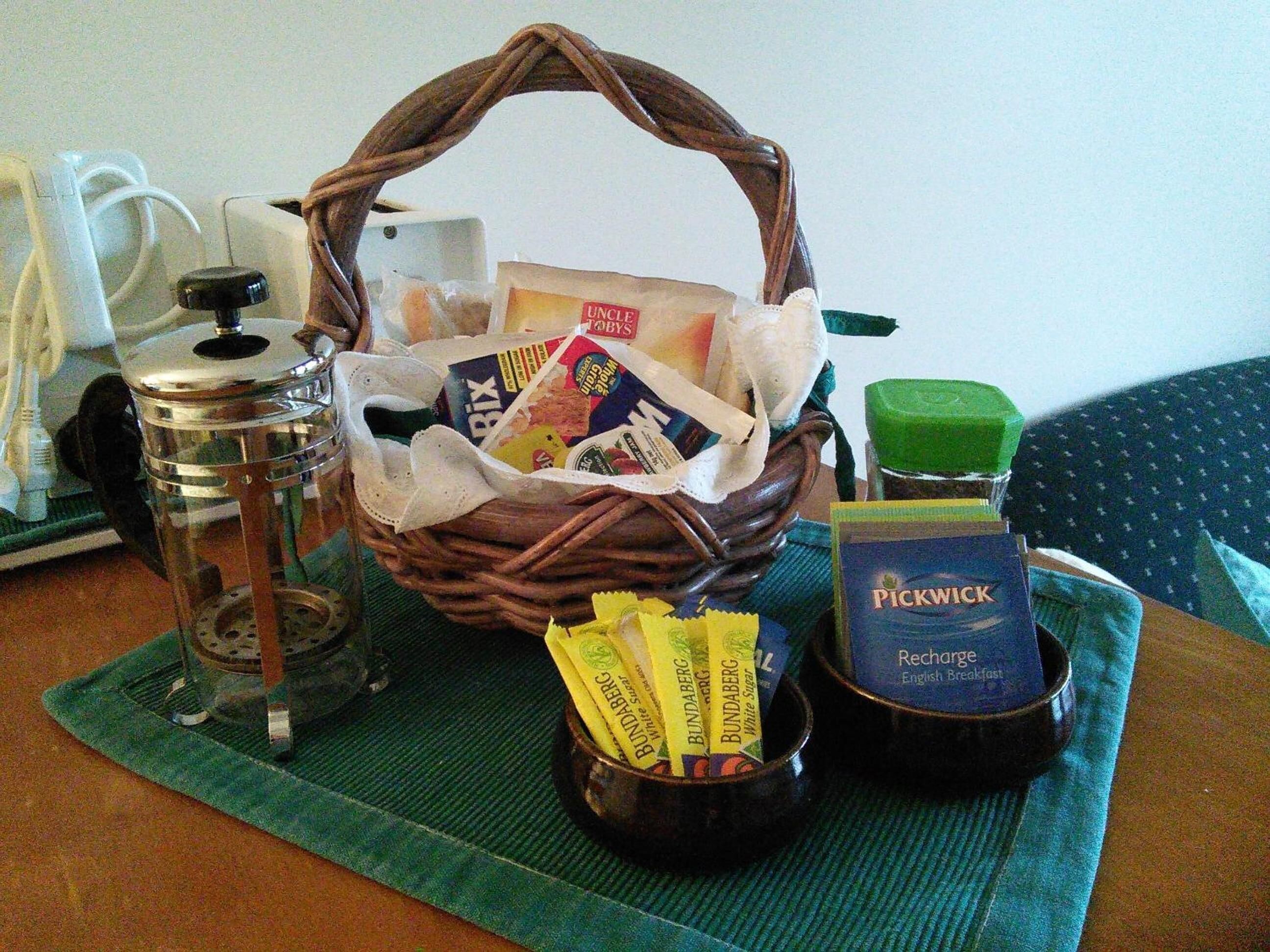 Ein Frühstücksbuffet mit Korb, Kaffeemaschine, Marmeladenglas und Tasse.