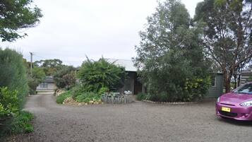 A gravel driveway leading to a house with a purple car parked on the right.