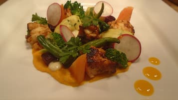 A square plate with a variety of food items including chicken, vegetables, and a sauce.
