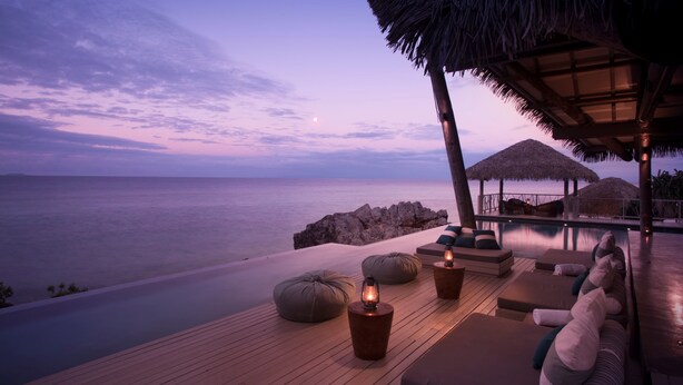 A serene beachside lounge with a wooden deck, lounge chairs, and a thatched roof structure. - Tadrai Island Resort-Fiji - All Inclusive (Mana Island)