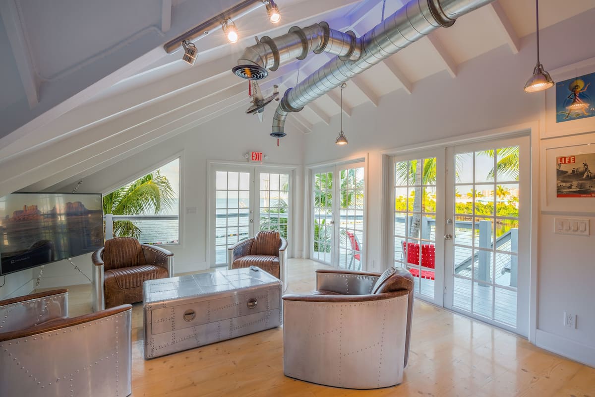A spacious room with large windows, a television, leather furniture, and a view of the outdoors.
