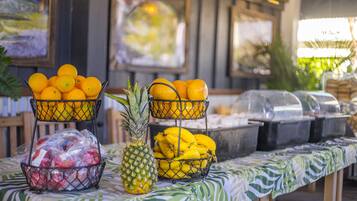 Una mesa de buffet con cestas de fruta y una piña.