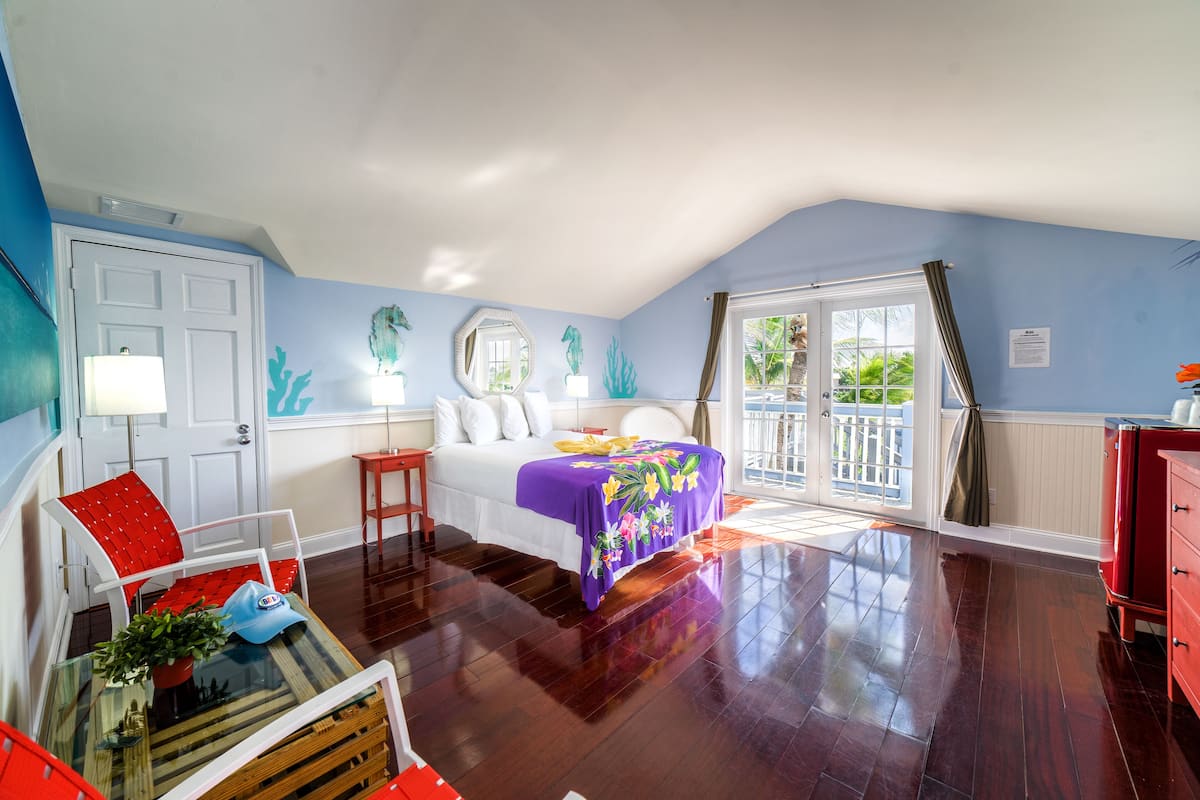A bedroom with a bed, a chair, a table, and a dresser.