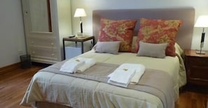 A neatly made bed with two towels, a nightstand with a lamp, and a dresser with a mirror. - Imagine Hotel Boutique (Buenos Aires)