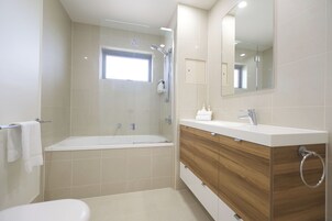 Un baño moderno con bañera, ducha, tocador con espejo y un inodoro.