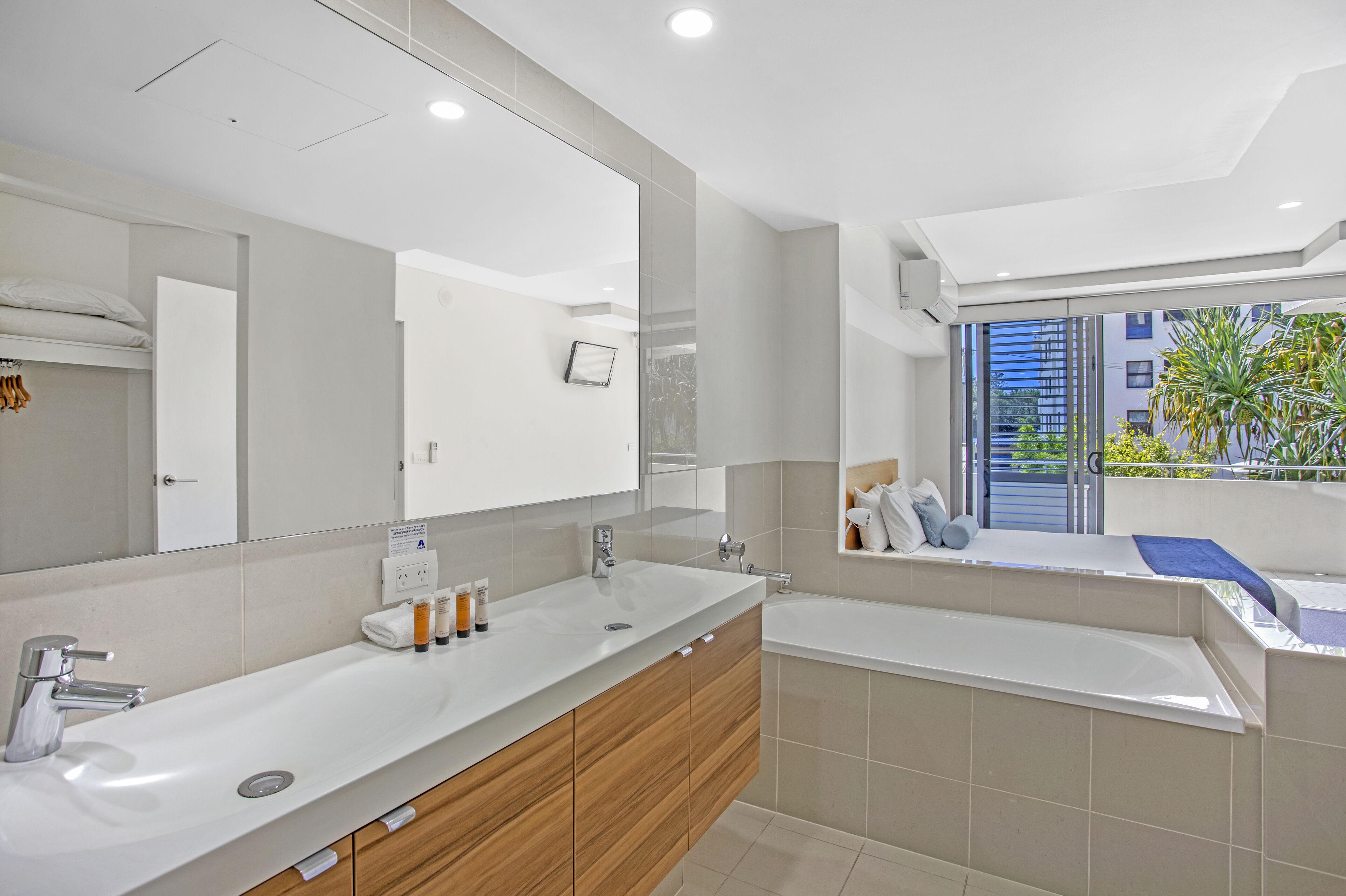 Un baño moderno con un espejo grande, un lavamanos y una bañera.