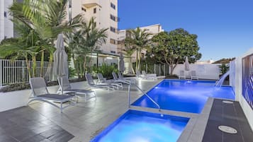 Una piscina al aire libre, sillones reclinables de piscina